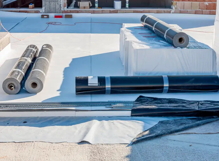 Construction site with a flat roof being waterproofed. The image shows a partially installed waterproof membrane, tools, and construction materials. The scene highlights the roofing process